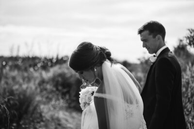 A bride reaching down to grab her veil during her photoshoot with aimee kelly photography in new plymouth