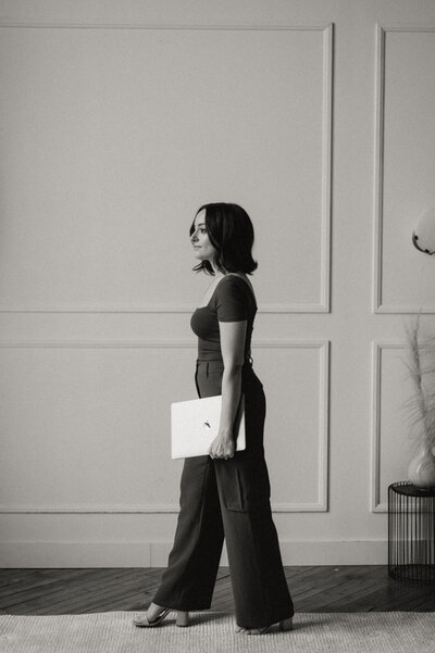 Female web designer walking confidently with a laptop, representing creative website design services for wellness brands and entrepreneurs.