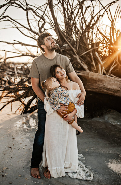 Family Photographer, a mother holds her son as dad holds a baby girl with a bow in her hair