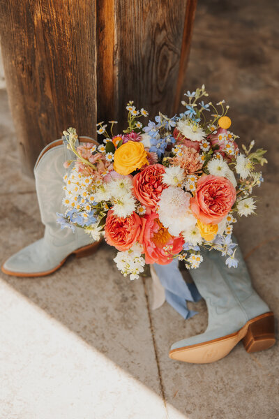 Detail photo of bridal cowgirl boots with the wedding flower bouquet.
