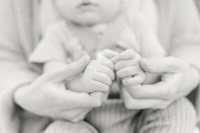 A black and white image of a newborn's hands being held by the mother's during a Rochester NY newborn photography session.