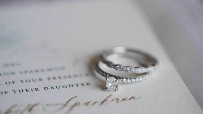 engagement ring and wedding ring laying on wedding invitation