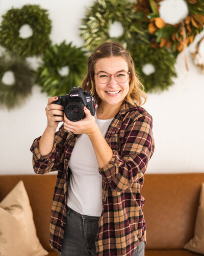 person smiling and holding a camera up towards the side of their face