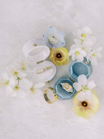 Flat lay of wedding stationery, rings and blue accents styled for Azure Romance wedding.