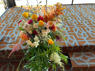 Vibrant floral arrangement in orange, red, and yellow hues on patterned stairs