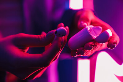 Neon photo ambient purple and red light, close up image of girl holding headphones