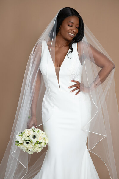 Bride wearing a cathedral length ribbon edged waterfall veil and holding a white and black bouquet