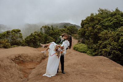 groom holding and dipping bride with jungle and mountains in the background