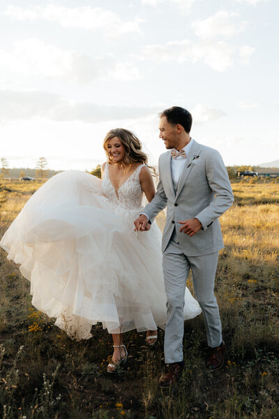 Arizona Luxury Wedding Photographer and Videographer Team Couple Running Through Field Holding Hands