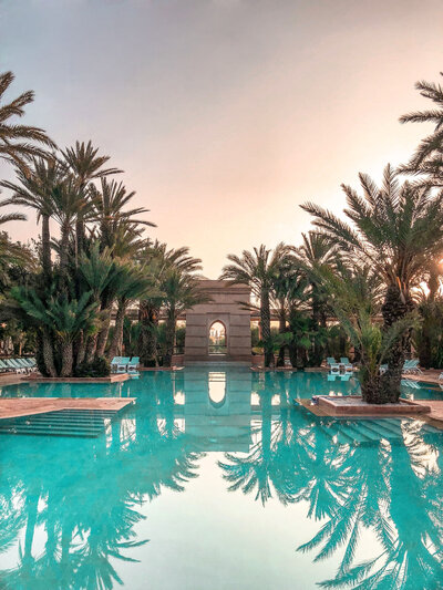 A blue hotel pool set amongst the palms