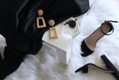 Gold earrings laying on black fabric on a white background
