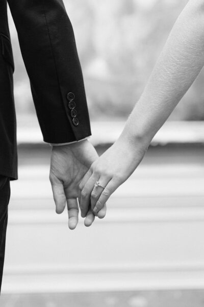 Black and white image of a couples hands touching lightly