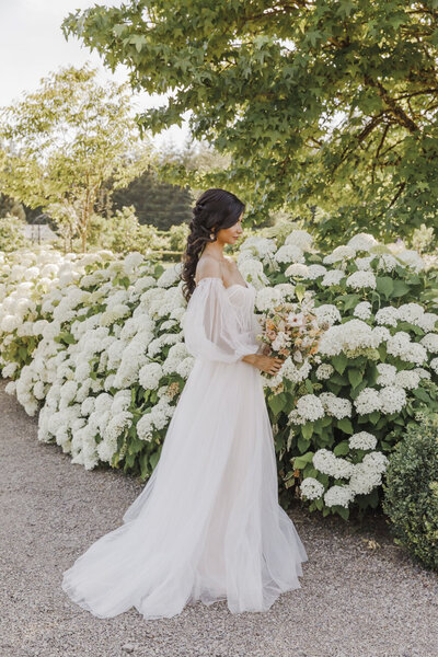 Bride posing by white flowers at Washington vineyard