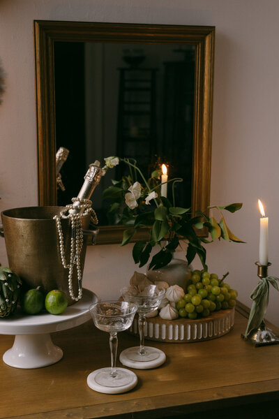 photo of champagne, grapes, candles and glasses all sitting on wooden table taken by Vineyard wedding photography Napa