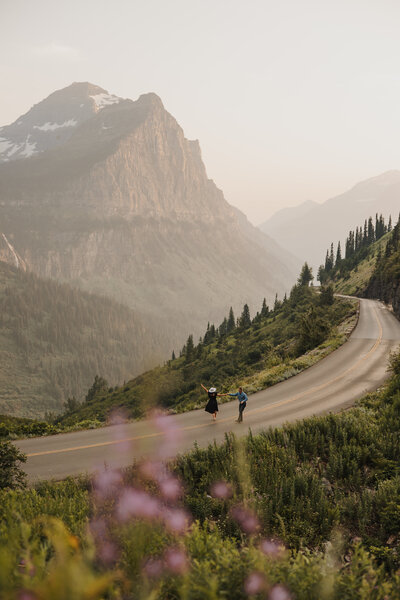 Scenic Glacier National Park elopement with a couple walking down the road in the distance, surrounded by mountain landscape.