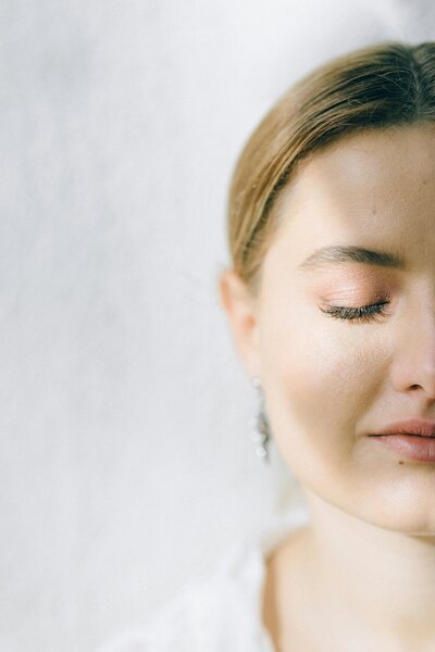 Woman standing peacefully with her eyes closed as the sun lights up half her face.