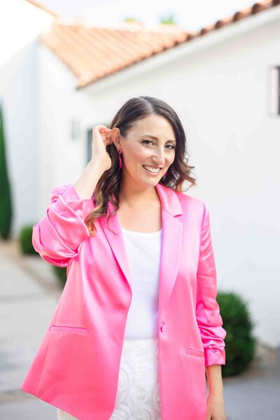 Brand strategist sharing authentic smile in vibrant pink blazer during outdoor professional photoshoot with natural lighting
