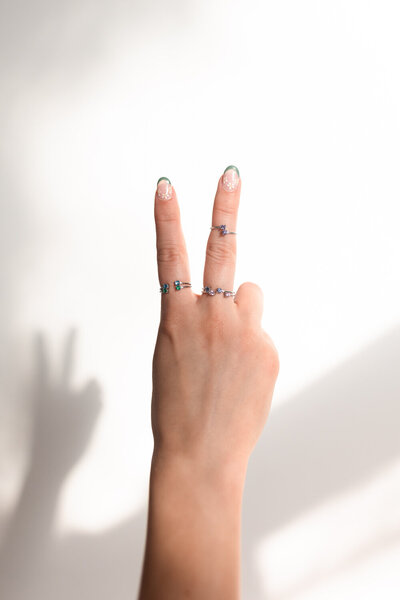 two fingers holding up a peace sign with rings on both fingers