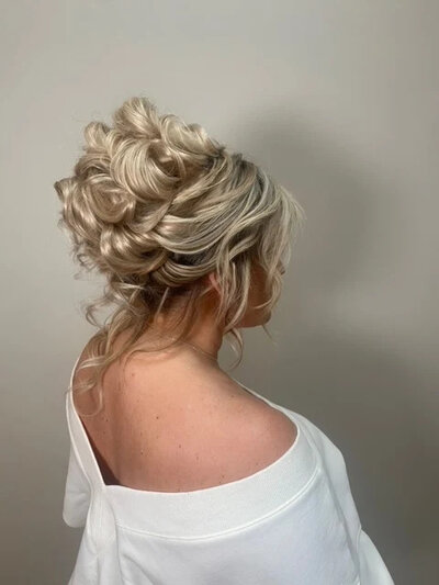 Image of a blonde bride showing off her updo styled by promise bridal artistry