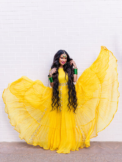 Woman with long dark hair and yellow long dress floating in the wind Indian look