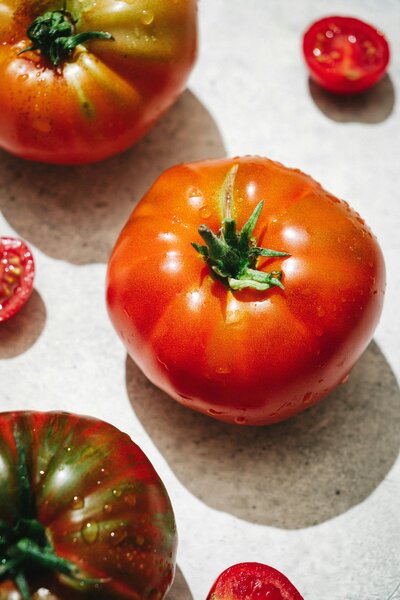 Heirloom tomatoes and cherry tomatoes on a white surface