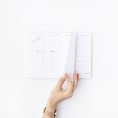 An overview of a desk calendar with a woman's hand turning the page