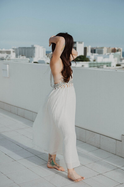 Ayurvedic skin specialist, Jen, wearing a white dress looking out at the city skyline.