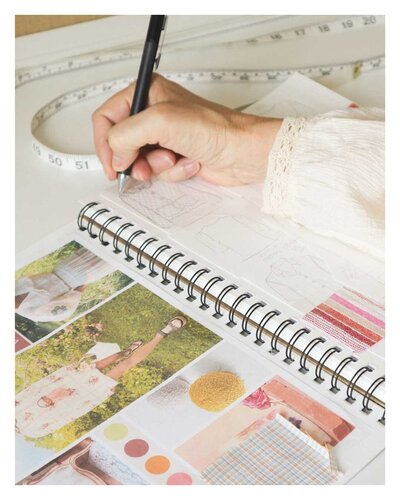 Notebook open with fashion design sketches, moodboard inspiration and collection ideas