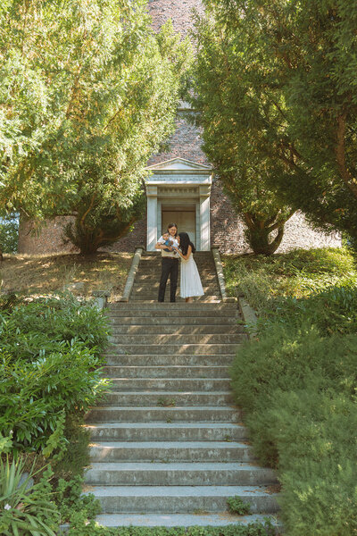 male and female on steps with newborn baby outdoors at city park