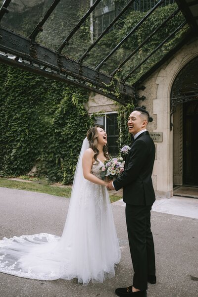 Bride and groom laughing outside venue