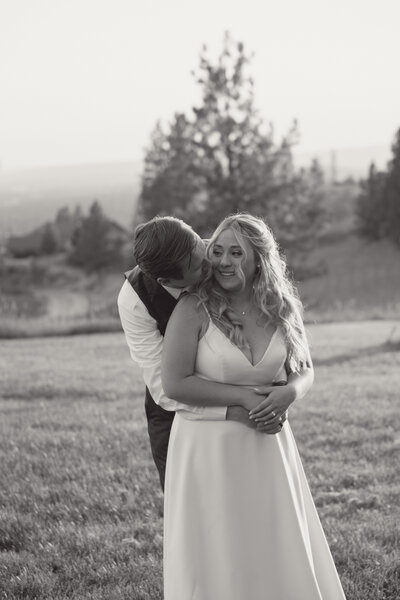 Bride and groom sitting on ground with their dog on their wedding day taken by Spokane Wedding Photograpeher