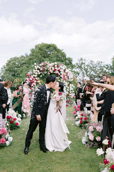 bride and groom kissing after the wedding ceremony with luxury red roses flower behind them 