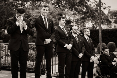 Emotional groom crying as groomsmen watch at outdoor wedding ceremony in New Jersey