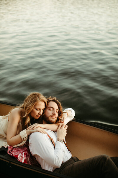 Bride and groom hugging in canoe on lake