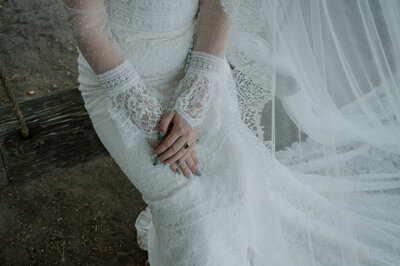 A close-up shot of the brides hands resting on her lace, detailed gown