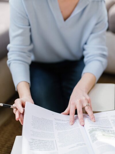 A copywriter leafs through pages of a magazine with a pen in hand