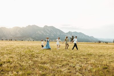 Family Holding Hands While Walking in Scenic Meadow