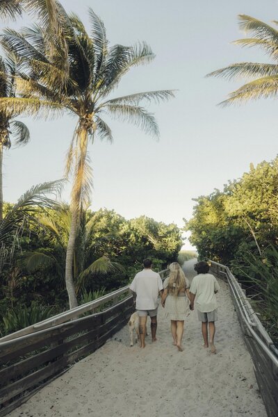 family holds hands and walks on the beach