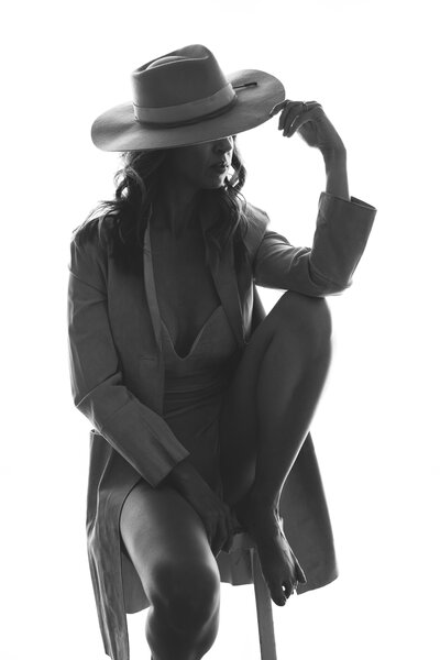 Woman sitting on a chair wearing a hat and a long coat