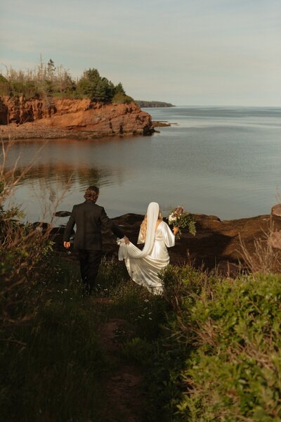 bride and groom walking to beach on wedding day in pei