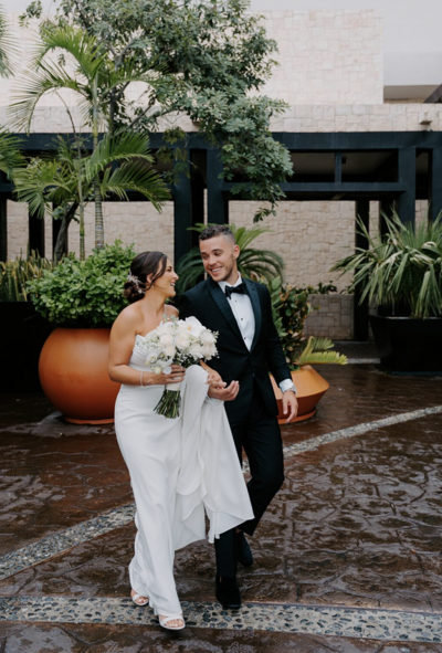 A young couple, likely a bride and groom, are posing together outdoors
