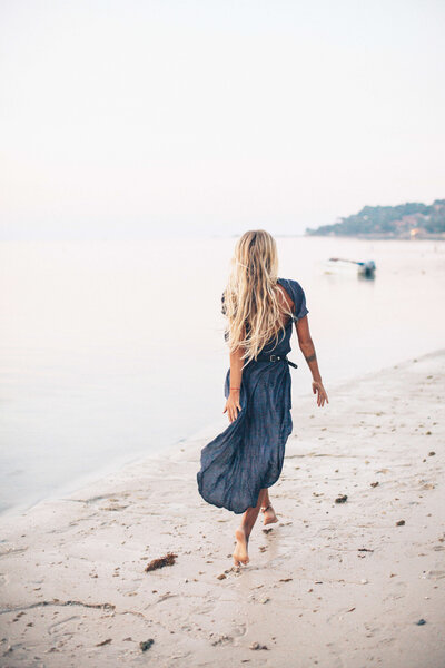 woman with long blonde hair wearing a blue dress on the beach
