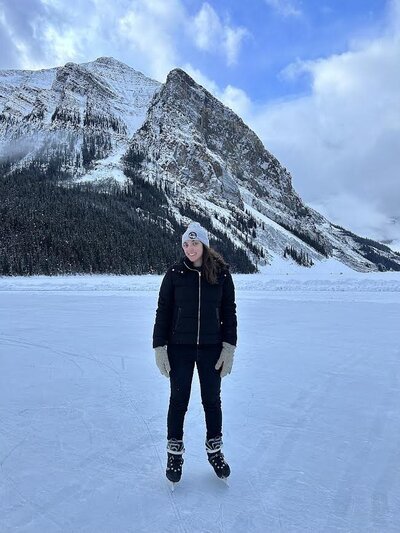 Me standing on the frozen Lake Louise in winter time, on ice skates, with snow covered mountains in the background