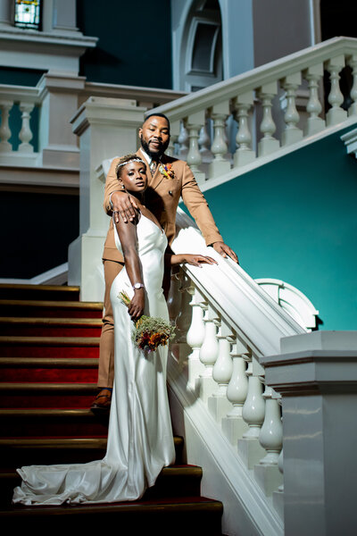 Wedding couple posing on grand red staircase