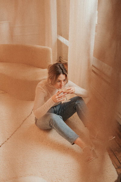 Girl sitting on floor and drinking iced coffee