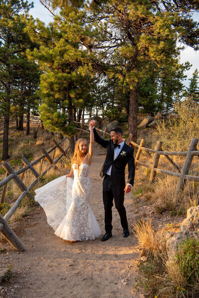 Two brides standing on a wooden bridge with  yellow trees surrounding them.