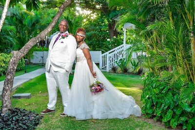 A bride and groom posing for a photo in a tropical garden.