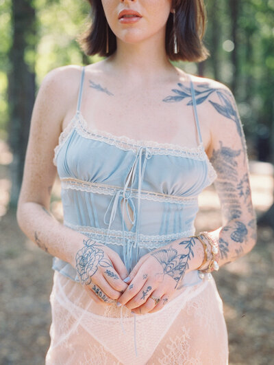 Film editorial photo of woman in a sheer outfit with tattoos on her arms