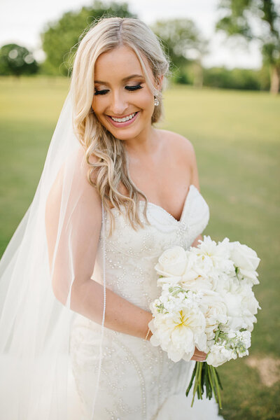 Bride wearing strapless dress with a long veil and white bouquet