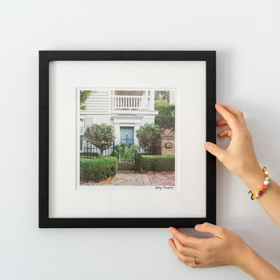 Hands holding up a black framed photography print of Charleston, SC by Abby Murphy